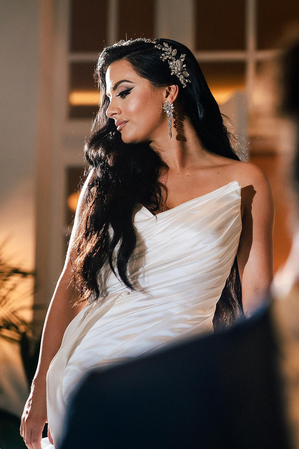 Close-up side view of the Chelsea wedding dress by Angela Kim Couture showing the asymmetric hand-draped satin bodice with diagonal pleating flowing from the sweetheart neckline.