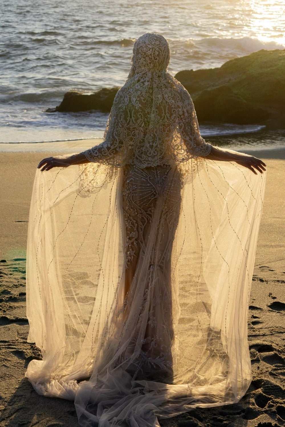 The Gigi couture bridal veil train flowing behind the bride, showcasing its full length and lace texture