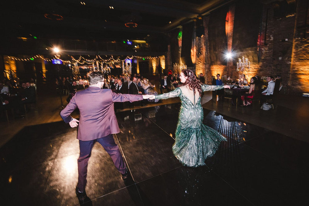 Dynamic motion shot of bride spinning on the dance floor in the Jessica forest green beaded wedding gown by Angela Kim Couture, the flowing trumpet skirt flaring dramatically and the crystal beadwork catching the reception lights in a blur of sparkle