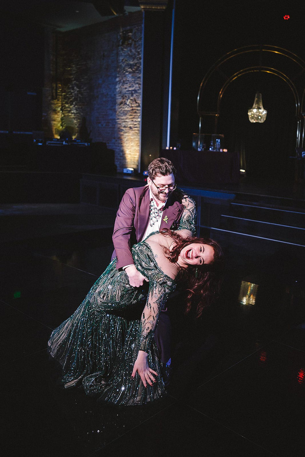 Groom dipping bride dramatically on the dance floor in the Jessica forest green hand-beaded wedding gown by Angela Kim Couture, the full trumpet silhouette and crystal-beaded illusion sleeves catching the reception lights