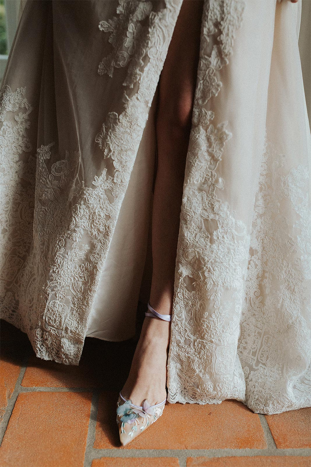 Close-up of the Morgan couture wedding dress by Angela Kim Couture showing the thigh-high slit on the A-line lace skirt with nude underlining visible through the sheer overlay