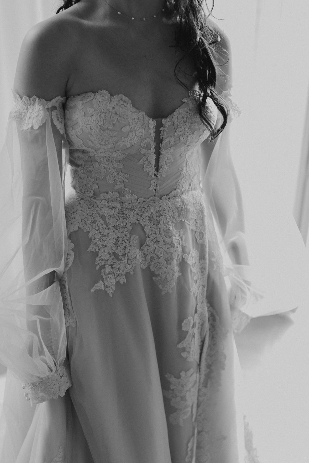 Close-up of the Morgan wedding dress by Angela Kim Couture showing the sweetheart lace corset bodice with deep V pleating and the sheer detachable bishop sleeve cuff