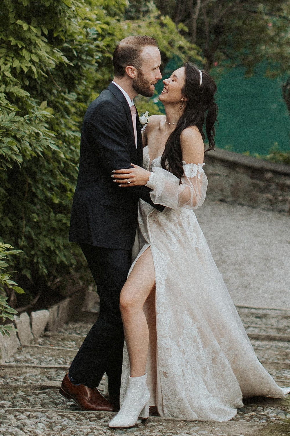 Morgan wedding dress by Angela Kim Couture with the thigh-high lace slit open, revealing the bride's leg and her white pearl-embellished ankle boots
