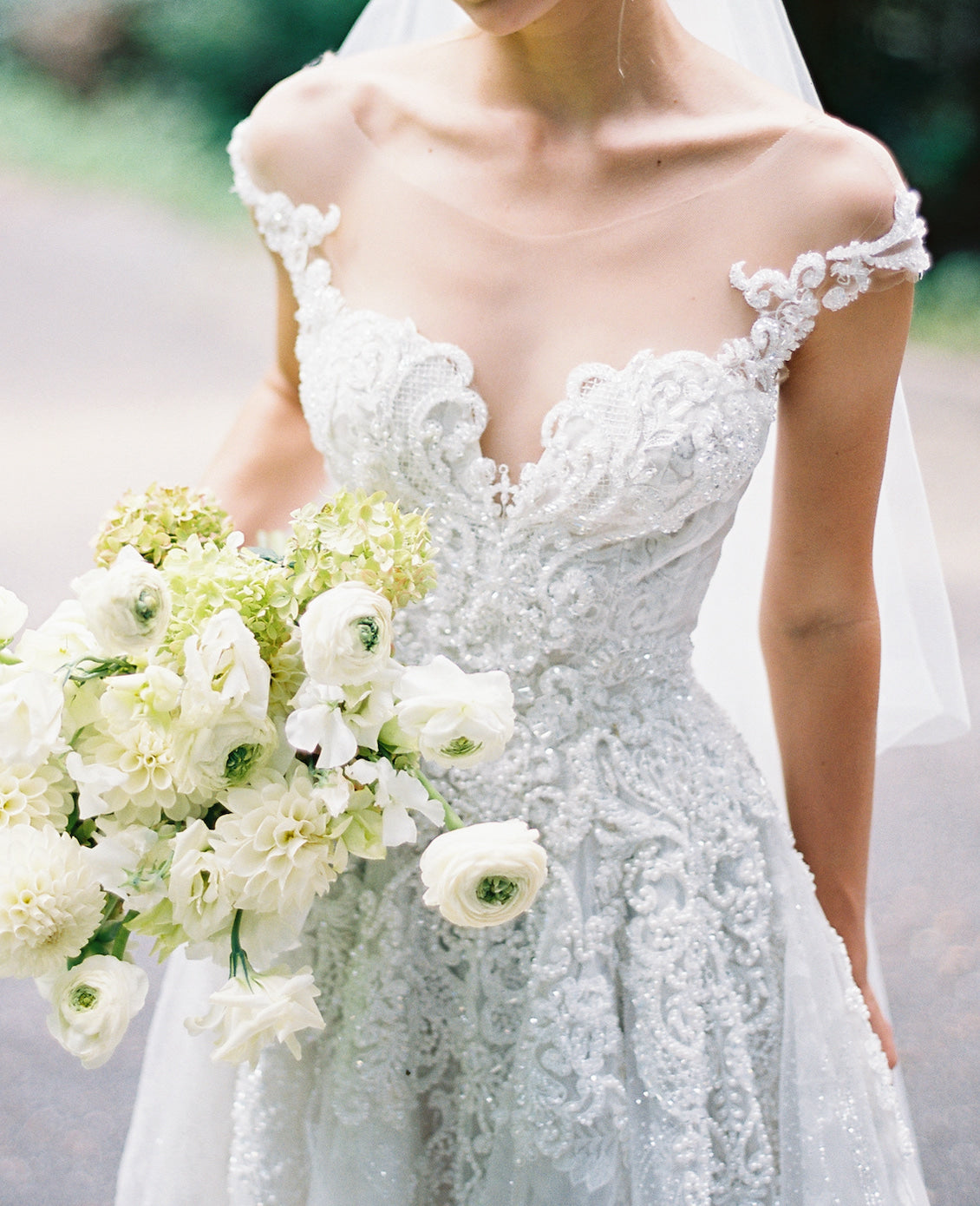 Bride in a couture lace wedding dress holding a bouquet of white flowers.