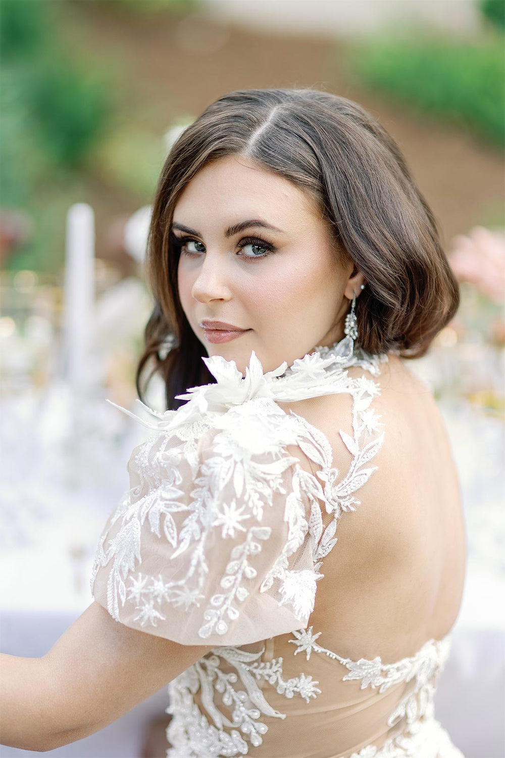 Outdoor bridal portrait of bride in the Rhea wedding dress with puff sleeves and illusion plunging neckline in a garden setting