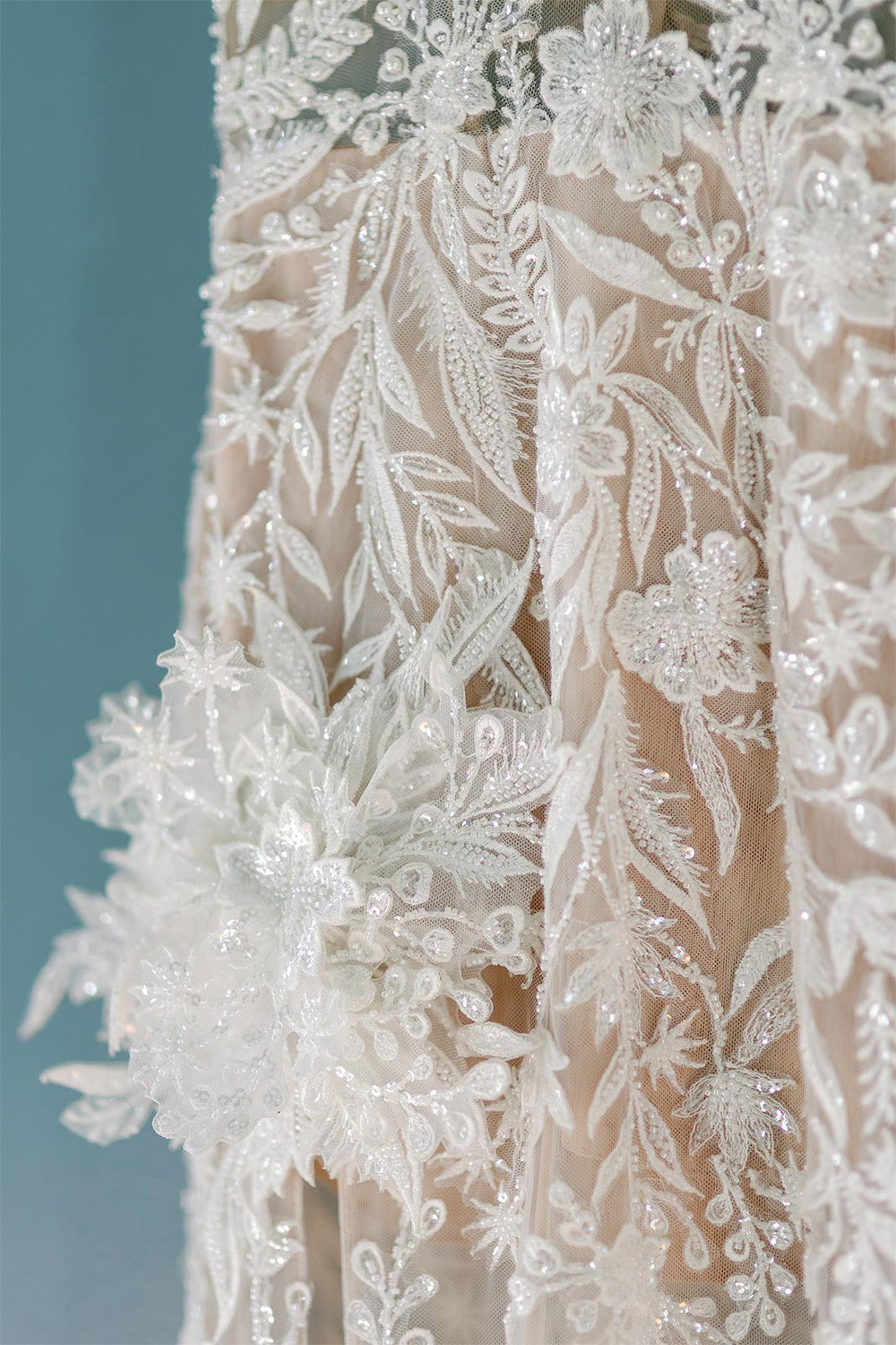 Close-up of the Rhea wedding dress embellished with delicate lace, beading and flower corsage