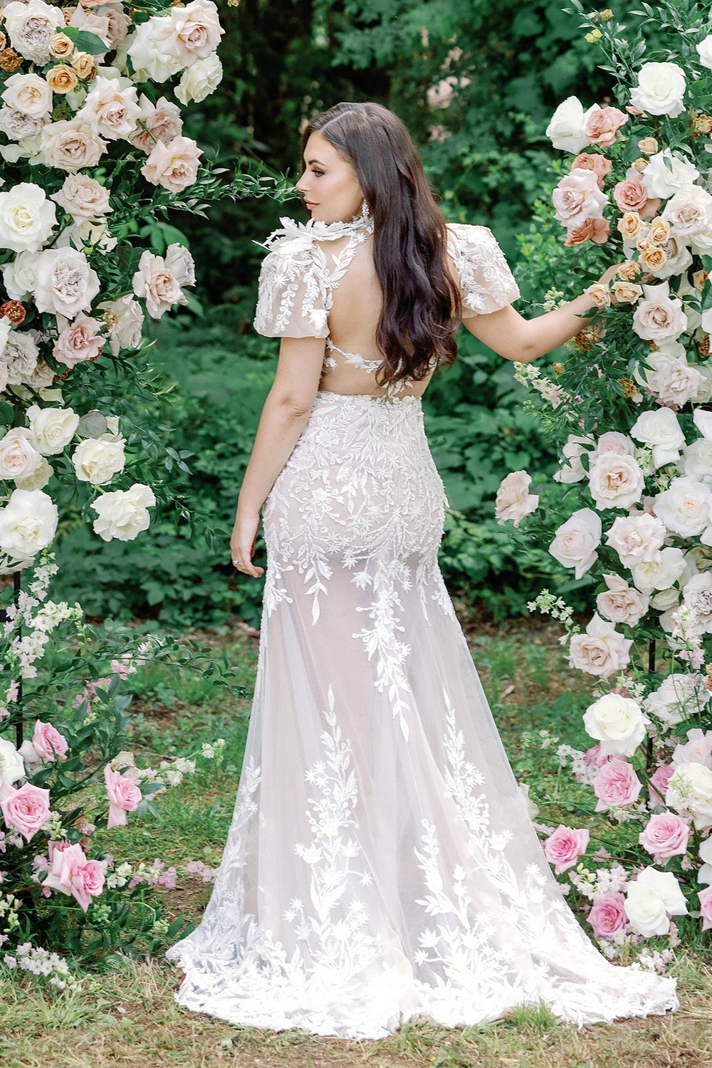 Back view of the Rhea couture wedding dress highlighting the illusion lace bodice and flowing skirt with flower corsage