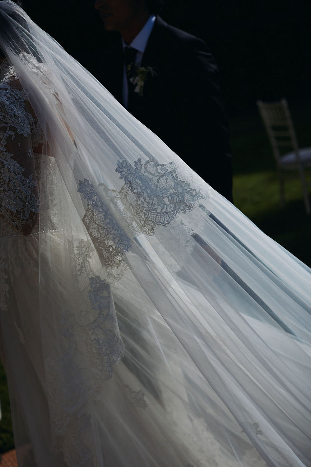 Dramatic close-up of Blaire's custom cathedral-length wedding veil with Chantilly lace edging draped in a church interior by Angela Kim Couture bespoke bridal design