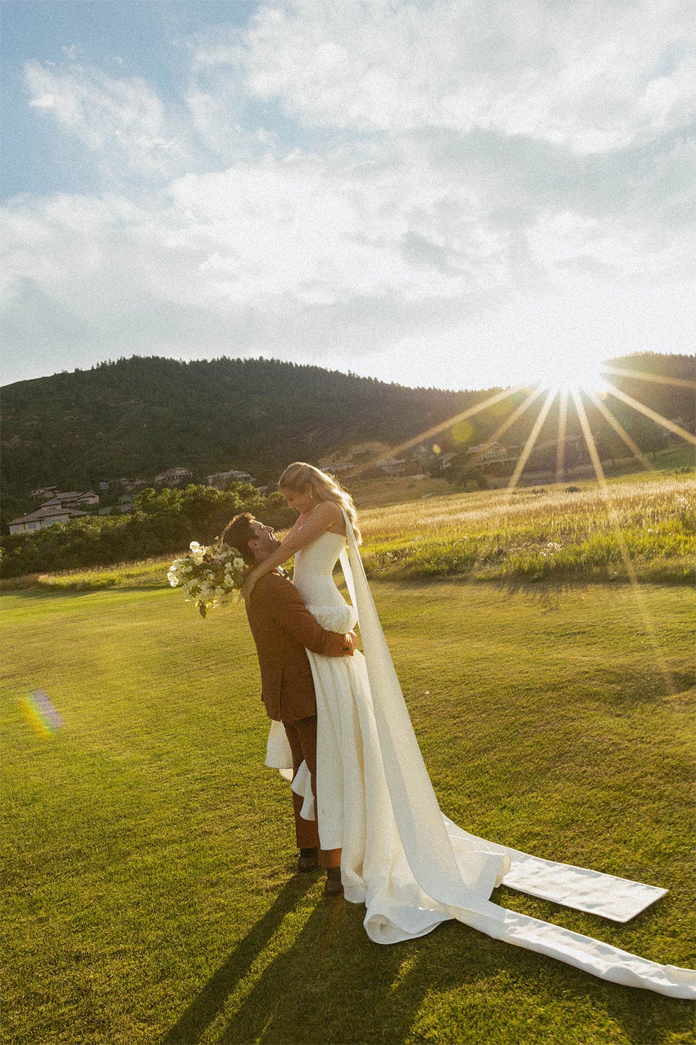 detail of Hannah's custom crepe wedding gown by Angela Kim Couture showing the voluminous A-line skirt with wide horsehair hem finish spread on green grass