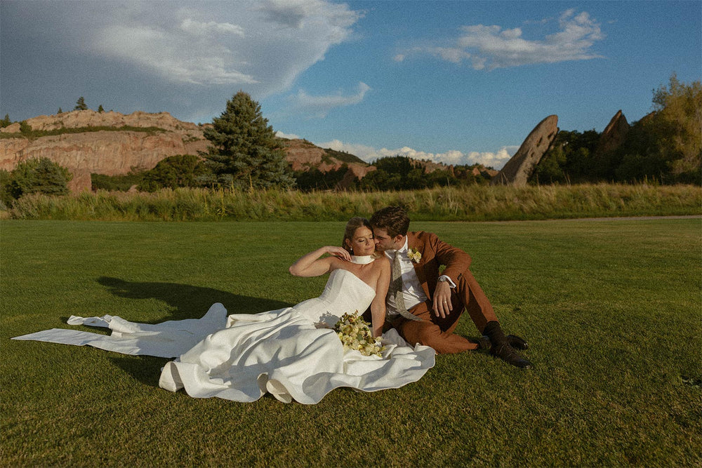 Detail view of Hannah's custom heavy-weight crepe A-line wedding skirt by Angela Kim Couture showing the wide horsehair hem finish and beautifully structured volume trailing on lush green grass