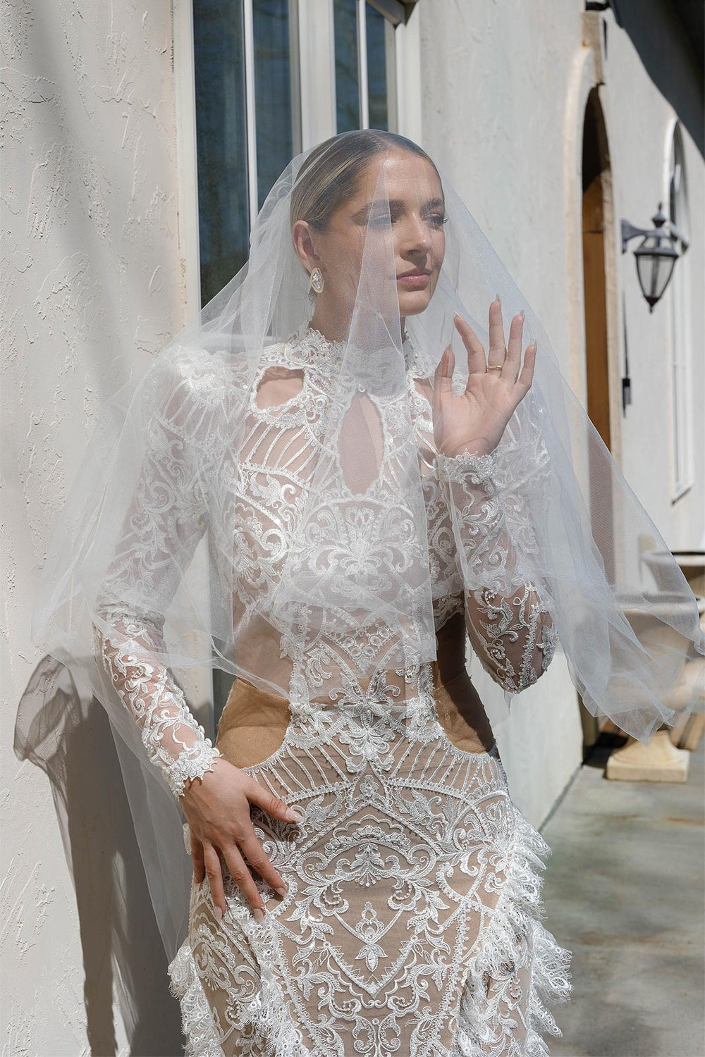 peytonIntimate portrait of bride Peyton under a sheer wedding veil against a textured stone wall,  wearing her custom high-neck lace wedding dress by Angela Kim Couture