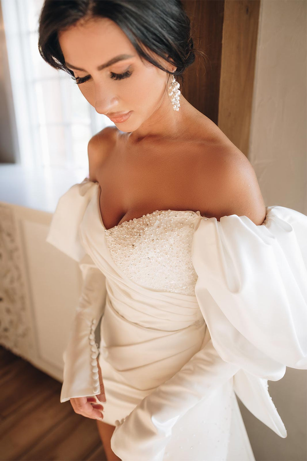 Romantic half-body portrait of bride in the Veronica wedding dress by Angela Kim Couture, showcasing sweetheart neck, ruched satin bodice, and juliette sleeve. 