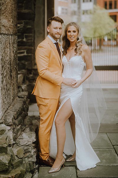 Elizabeth in her high slit wedding gown posing with Jacob for a wedding portrait.