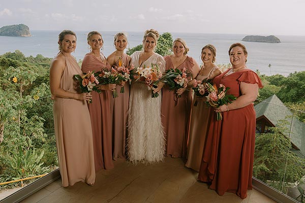 Leah posing with her bridesmaids on a balcony over the ocean.